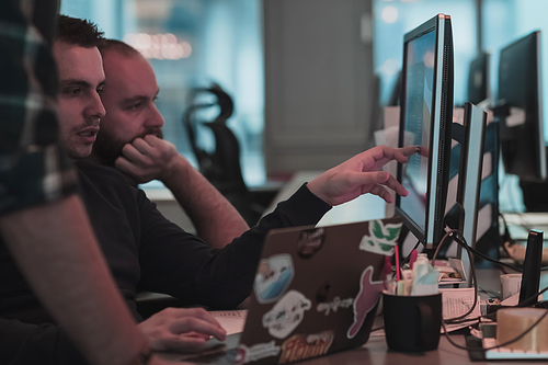 A photo of three men staring intently at a computer while sitting in a modern office. Selective focus. High-quality photo