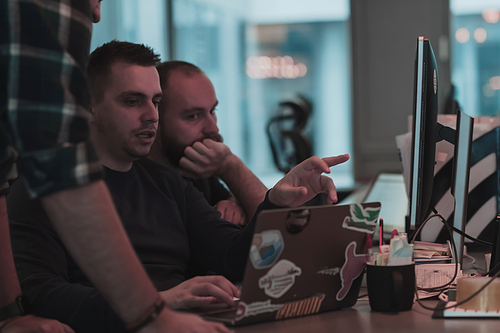 A photo of three men staring intently at a computer while sitting in a modern office. Selective focus. High-quality photo