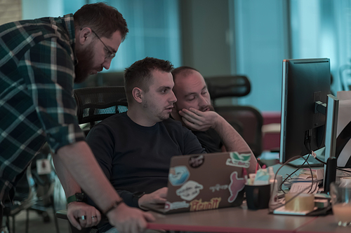 A photo of three men staring intently at a computer while sitting in a modern office. Selective focus. High-quality photo