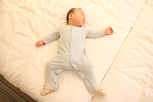 하얀색 호텔 침대 위에서 잠든 아기