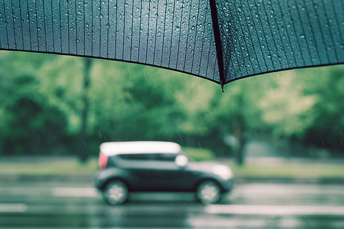 비 내리는 날의 거리의 자동차와 우산을 들고 있는 보행자