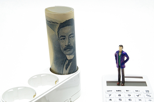 전기 콘센트에 꽂힌 일본 지폐와 계산기위의 사람