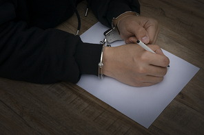 범죄와 법률 - 진술서를 작성하는 수갑을 찬 범죄자의 손