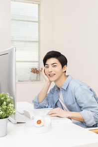 슬기로운 취준생 생활 - 컴퓨터 모니터 앞에 앉아 턱을 괴며 웃고있는 청년