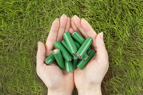 생활 속 에너지 - 잔디 배경, 두 손 위에 놓여진 초록색 에코 건전지들