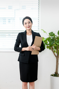 검은색 정장입은 여성이 차트를 들고 미소짓고 있는 장면 이미지 사진