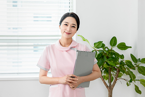 간호사 유니폼 입고 있는 여성이 차트들고 미소 짓고 있는 장면 이미지 사진