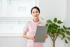 간호사 유니폼 입고 있는 여성이 차트들고 미소 짓고 있는 장면 이미지 사진