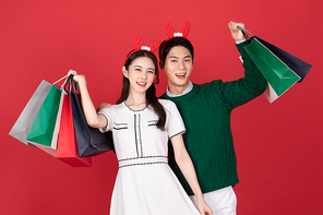 크리스마스 쇼핑이벤트 컨셉 루돌프 머리띠한 커플이 쇼핑백들고 있는 사진 이미지
