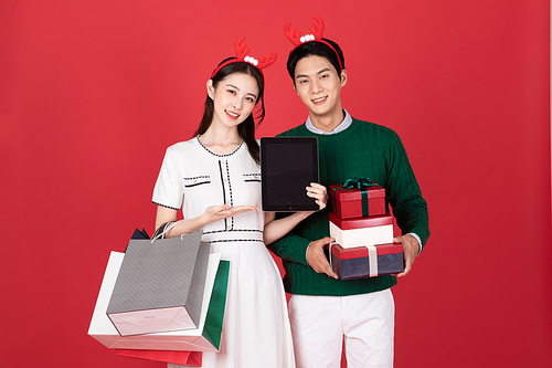 크리스마스 쇼핑이벤트 컨셉 루돌프 머리띠한 커플이 타블렛과 쇼핑백들고 있는 사진 이미지