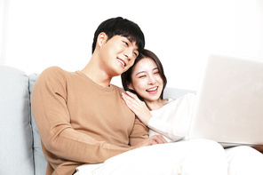 소파에 앉아 노트북으로 즐거운 시간 보내고 있는 커플