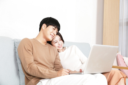 소파에 앉아 노트북으로 즐거운 시간 보내고 있는 커플