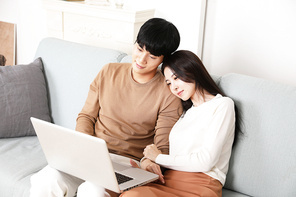 소파에 앉아 노트북으로 즐거운 시간 보내고 있는 커플