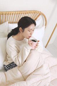 겨울실내일상_침대에서 커피마시는 여성 사진
