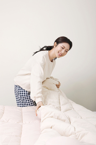 겨울실내일상_침대 정리하는 여성 사진