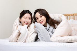 겨울실내일상_침대에서 이불덮고 있는 여성 2명 사진