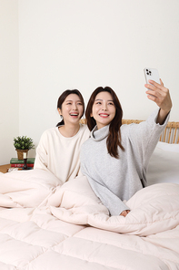 겨울실내일상_침대에서 셀카찍고 있는 여성 2명 사진