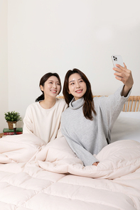 겨울실내일상_침대에서 셀카찍고 있는 여성 2명 사진