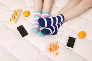 겨울실내일상_침대에 과일 과자 스마트폰과 여성 2명이 수면양말 신고 있는 사진