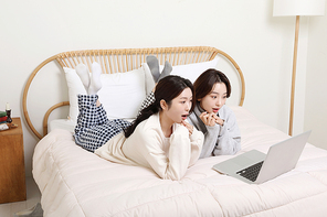 겨울실내일상_침대에서 노트북으로 동영상보는 여성 2명 사진
