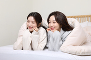 겨울실내일상_침대에서 티비보며 웃고 있는 여성 2명 사진