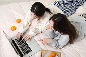 겨울실내일상_침대에서 스마트폰보고 있는 여성 2명 사진