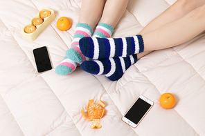 겨울실내일상_침대에 과일 과자 스마트폰과 여성 2명이 수면양말 신고 있는 사진