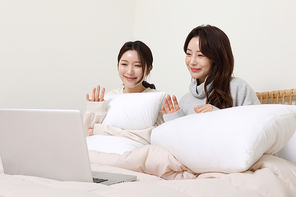 겨울실내일상_침대에서 노트북으로 영상통화 하는 여성 2명 사진
