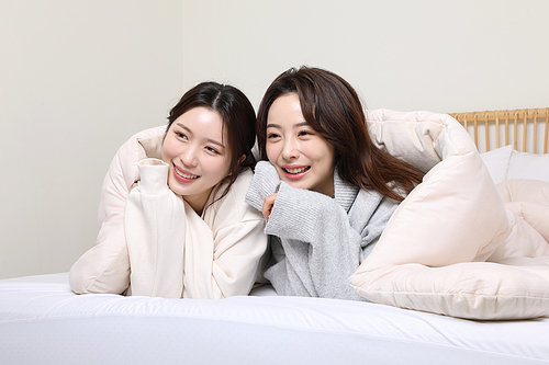 겨울실내일상_침대에서 티비보며 웃고 있는 여성 2명 사진
