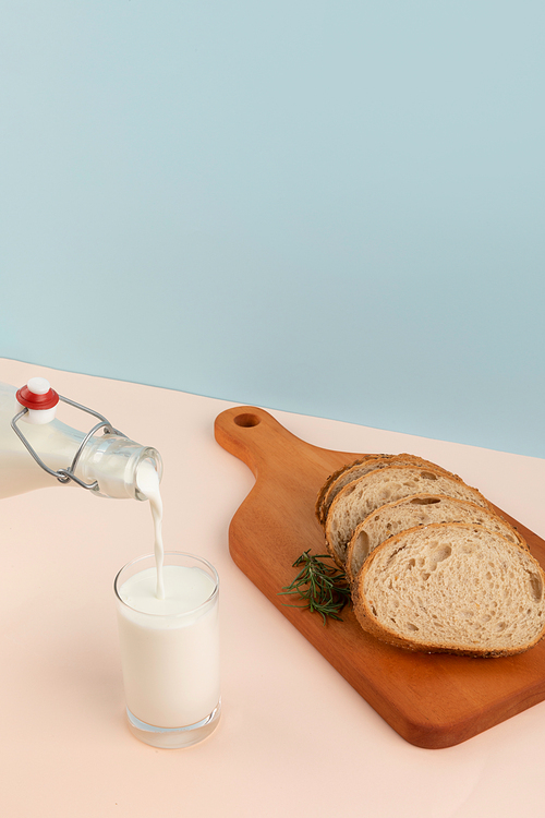 유제품_하늘색 배경 호밀빵과 컵에 우유 따르는 사진