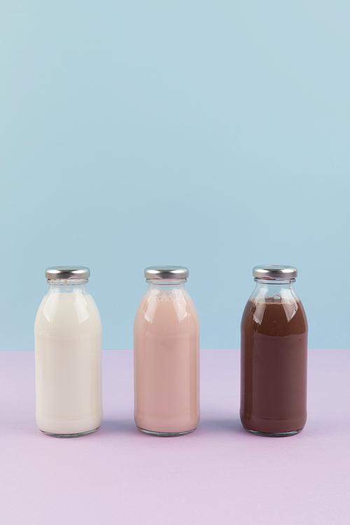 유제품_하늘색과 보라색 배경 병에 담긴 흰우유 딸기우유 초코우유 사진