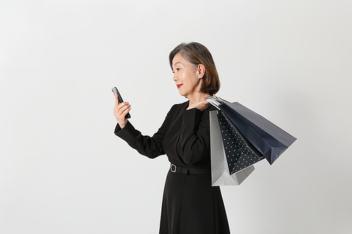 시니어여성_쇼핑백과 스마트폰 들고 있는 중년여성 사진