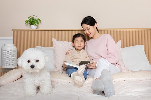 반려견_침대에 앉아 책읽고 있는 모녀와 강아지 사진