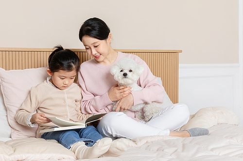 반려견_침대에 앉아 책읽고 있는 모녀와 강아지 사진