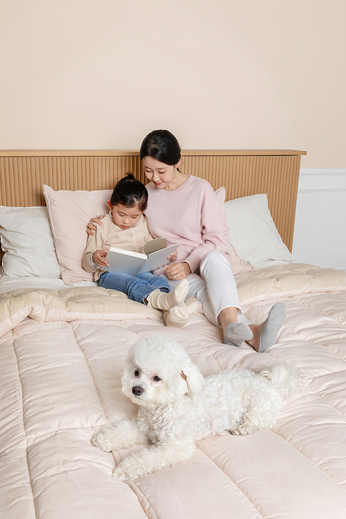 반려견_침대에 책 읽고있는 모녀와 강아지 클로즈업 사진