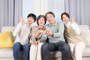 나의가족_조부모님과 손주들이 들고있는 주택모형 사진 이미지