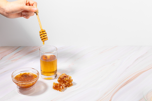 꿀_유리컵에 담긴 꿀물에 꿀을 넣는 핸드모션 사진 이미지