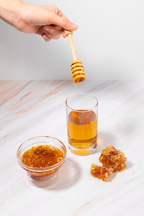 꿀_유리컵에 담긴 꿀물에 꿀을 넣는 핸드모션 사진 이미지