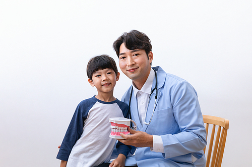 어린이의료_치아 모형을 들고 있는 의사와 어린이 사진 이미지