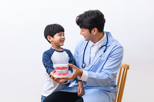 어린이의료_치아 모형을 들고 있는 의사와 어린이 사진 이미지