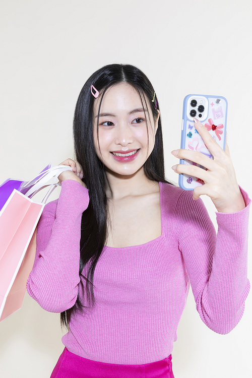 Y2K 라이프스타일_스마트폰과 쇼핑백 들고 있는 여성 컨셉 사진
