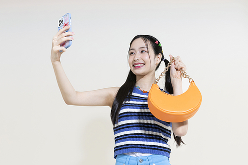 Y2K 라이프스타일_핸드백과 스마트폰 들고 있는 여성 컨셉 사진