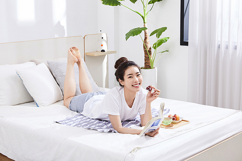 여름일상_침대 위 엎드려서 과일 먹는 여자 사진 이미지