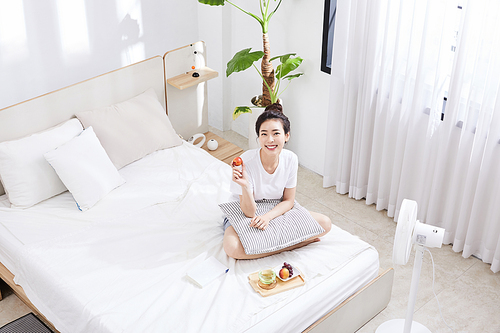 여름일상_침대 위 앉아서 과일을 든 여자 사진 이미지
