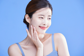 피부를 만지며 웃는 여자 사진 이미지