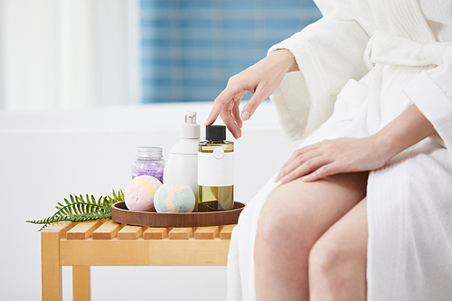 목욕 용품과 욕조에 기대 앉아있는 여성 사진 이미지