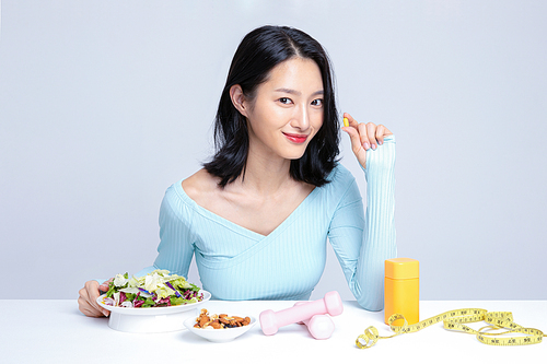 건강한 식사_식단과 운동기구 앞에서 알약을 들고있는 여성 사진 이미지