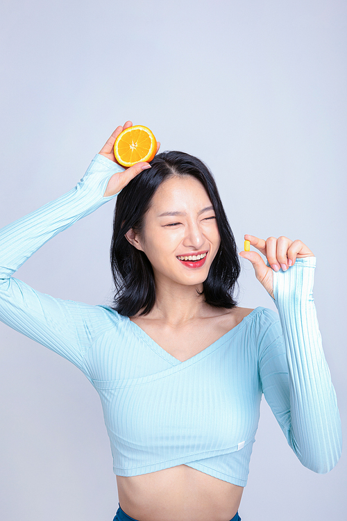 건강한 식사_알약과 오렌지를 들고있는 여성 사진 이미지