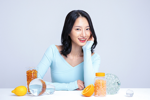 건강한 식사_알약 레몬 귤 오렌지 앞에 앉아있는 여성 사진 이미지