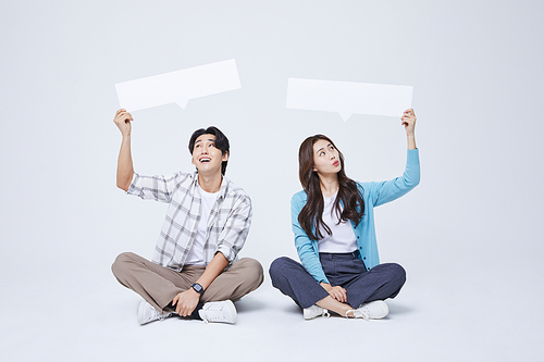 협동 비즈니스_양반다리를 하고 비어있는 메시지 종이를 들고 앉아있는 남자와 여자 사진 이미지